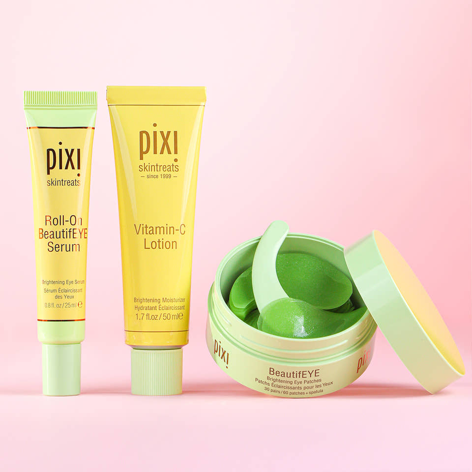 Pixi skincare products including Roll-on BeautifEYE serum, Vitamin-C lotion, and BeautifEYE brightening eye patches on a pink background view 1